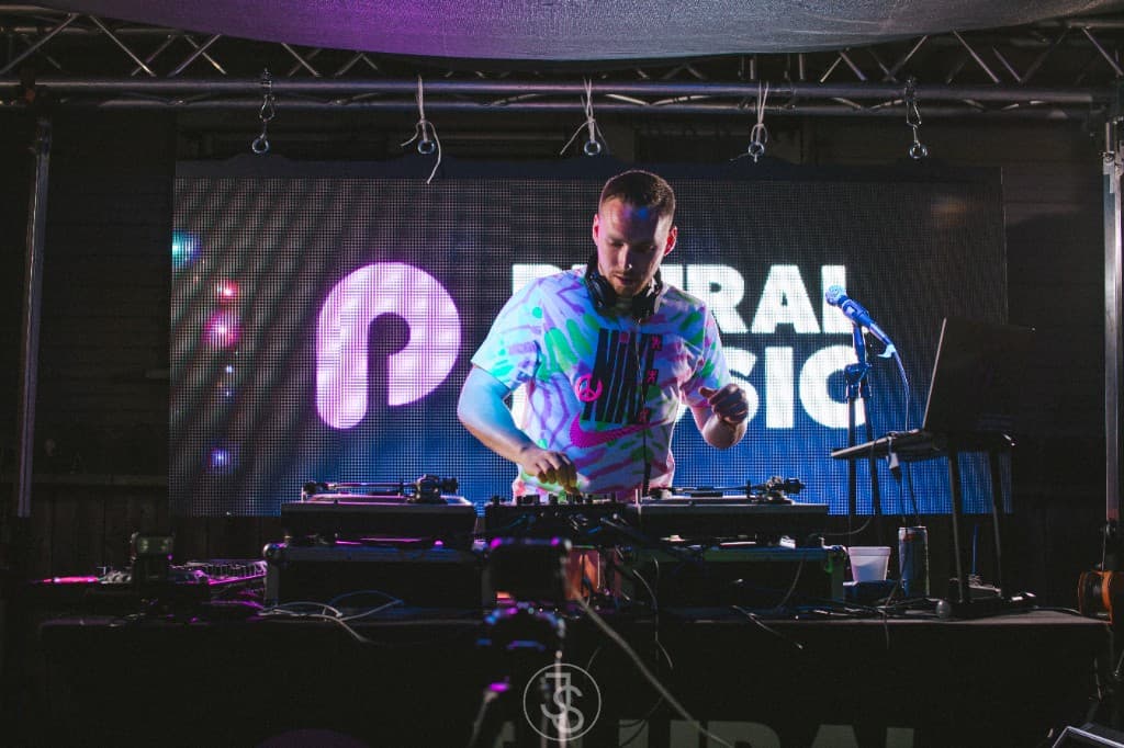 Jamie Selects DJing at a Plural Music backyard event, headphones around his neck